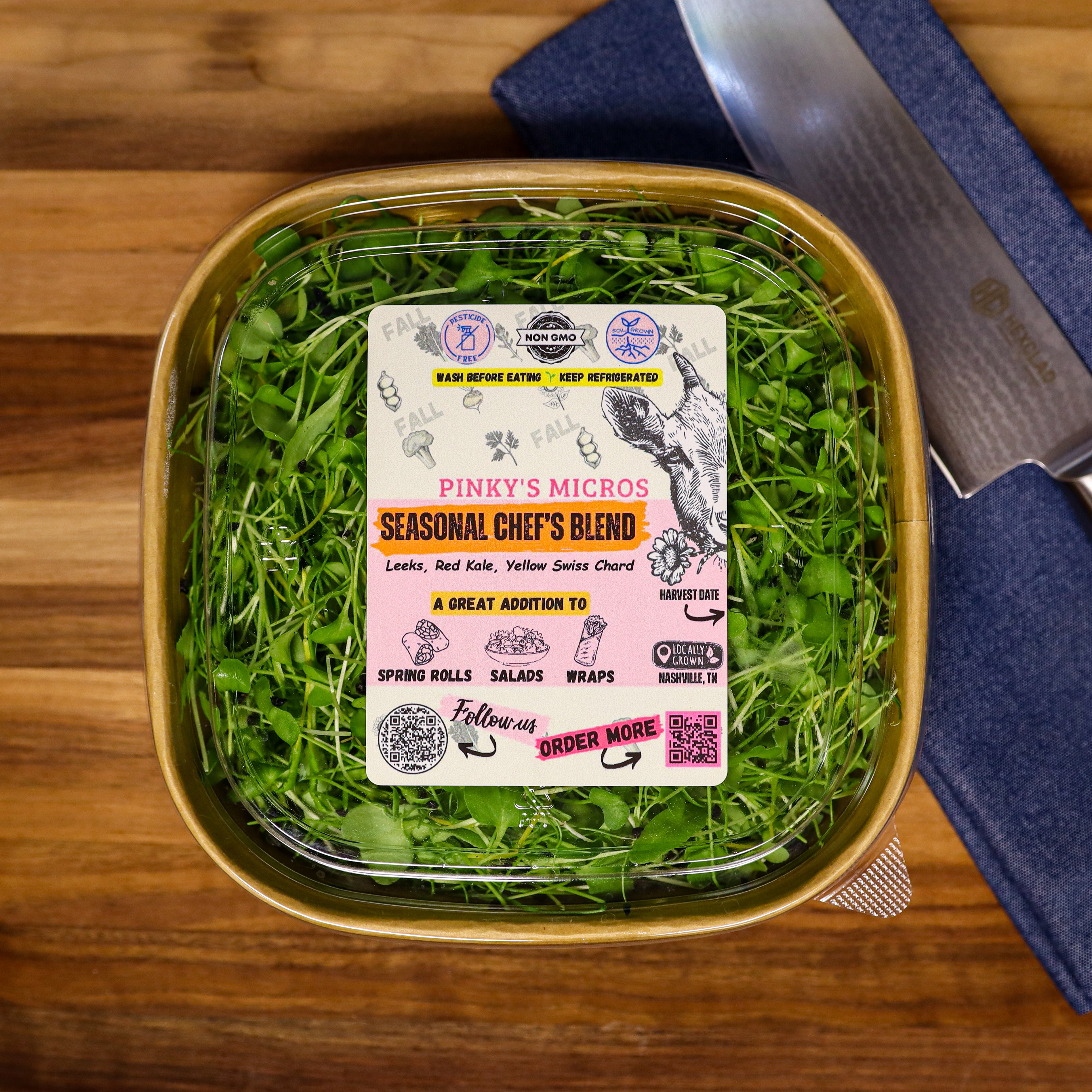 Container of Pinky's Micros microgreens with a knife on a wooden surface